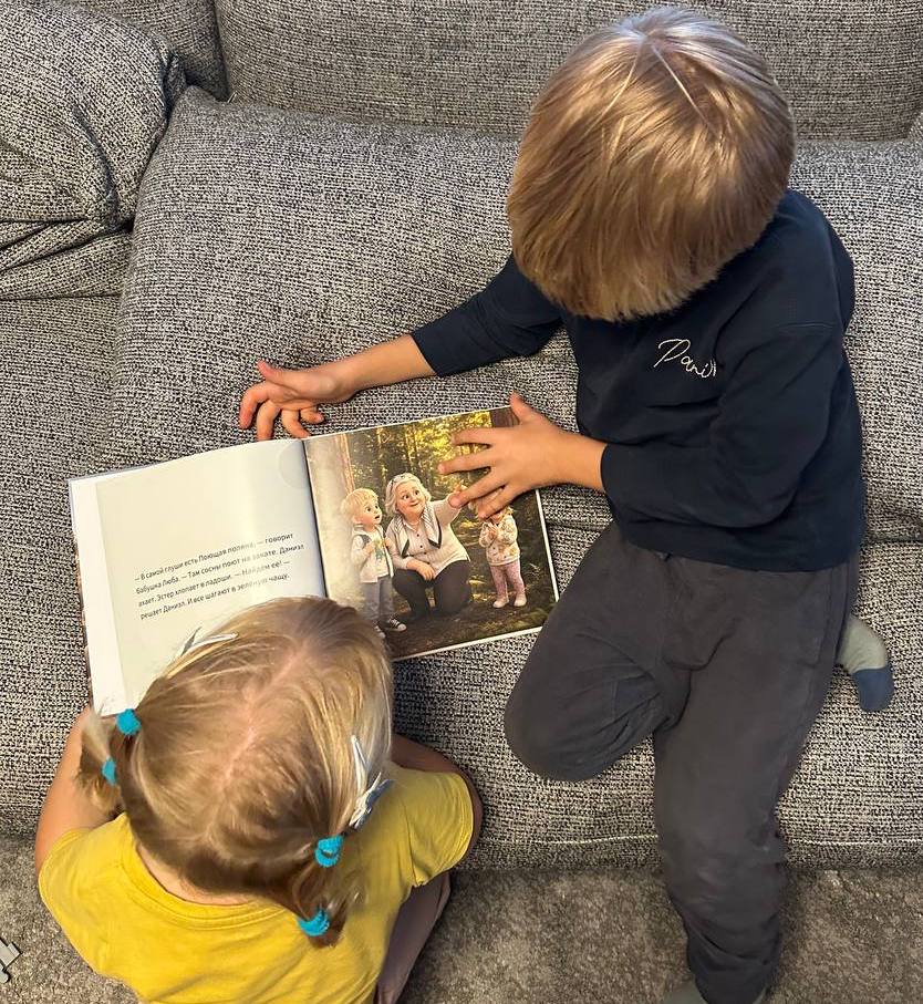 Two children on a sofa reading their open hardcover Toto book
